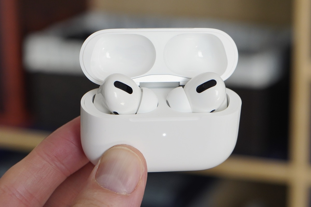 Seseorang memegang sepasang AirPods pro yang terletak di dalam wadahnya.